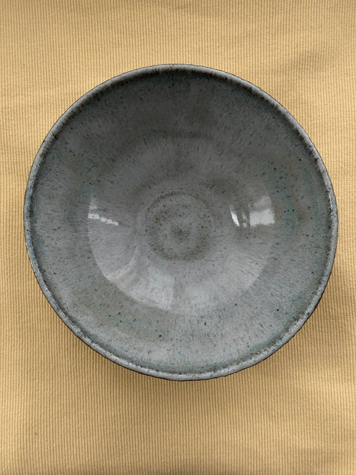 Dark gray ceramic bowl on a gold textured surface