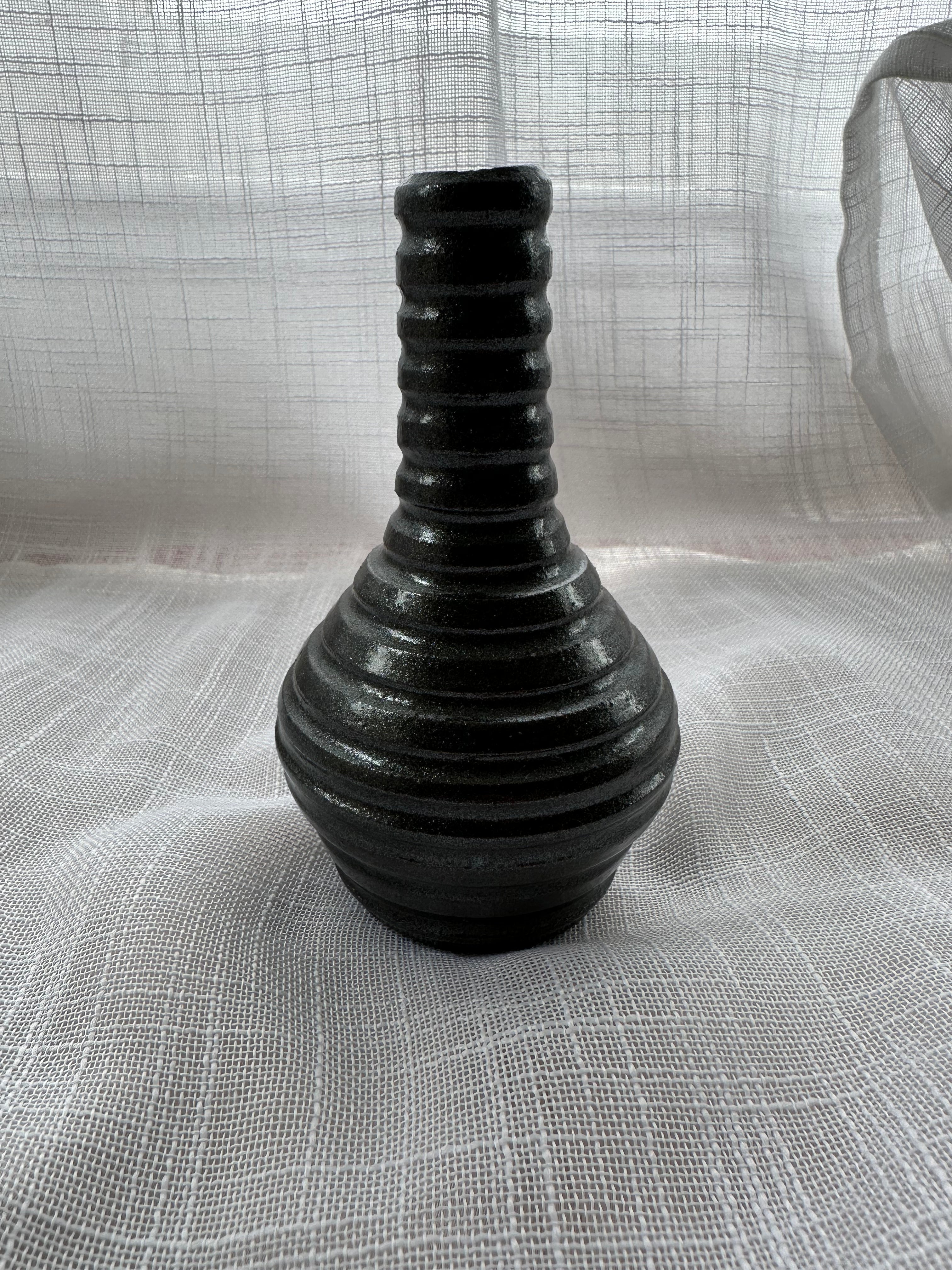 Black ribbed vase on a textured gray surface