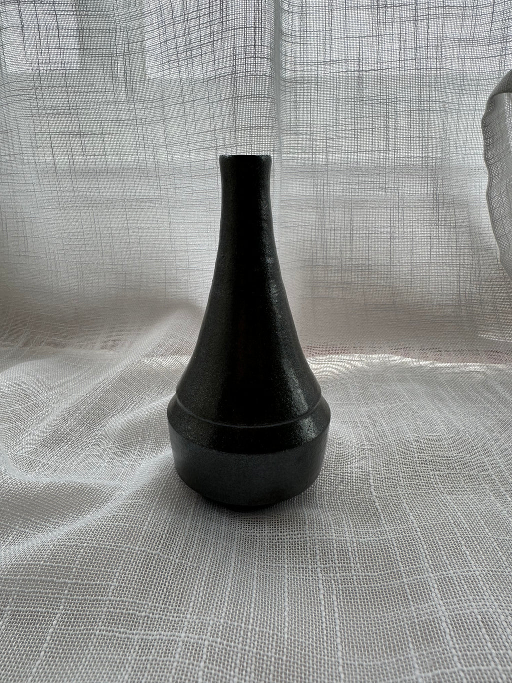 Black vase on a textured gray surface