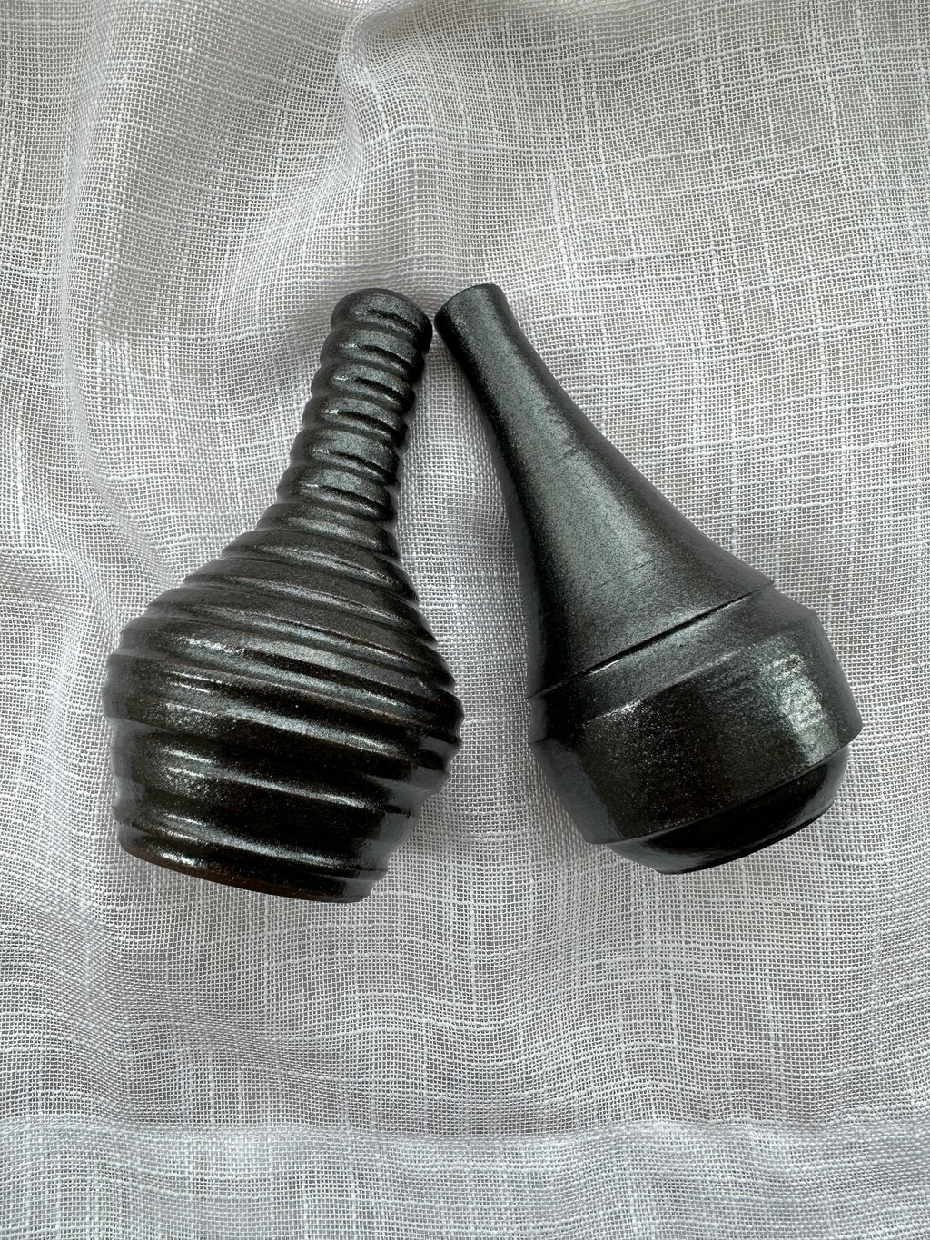 Two black ceramic vases on a textured gray background