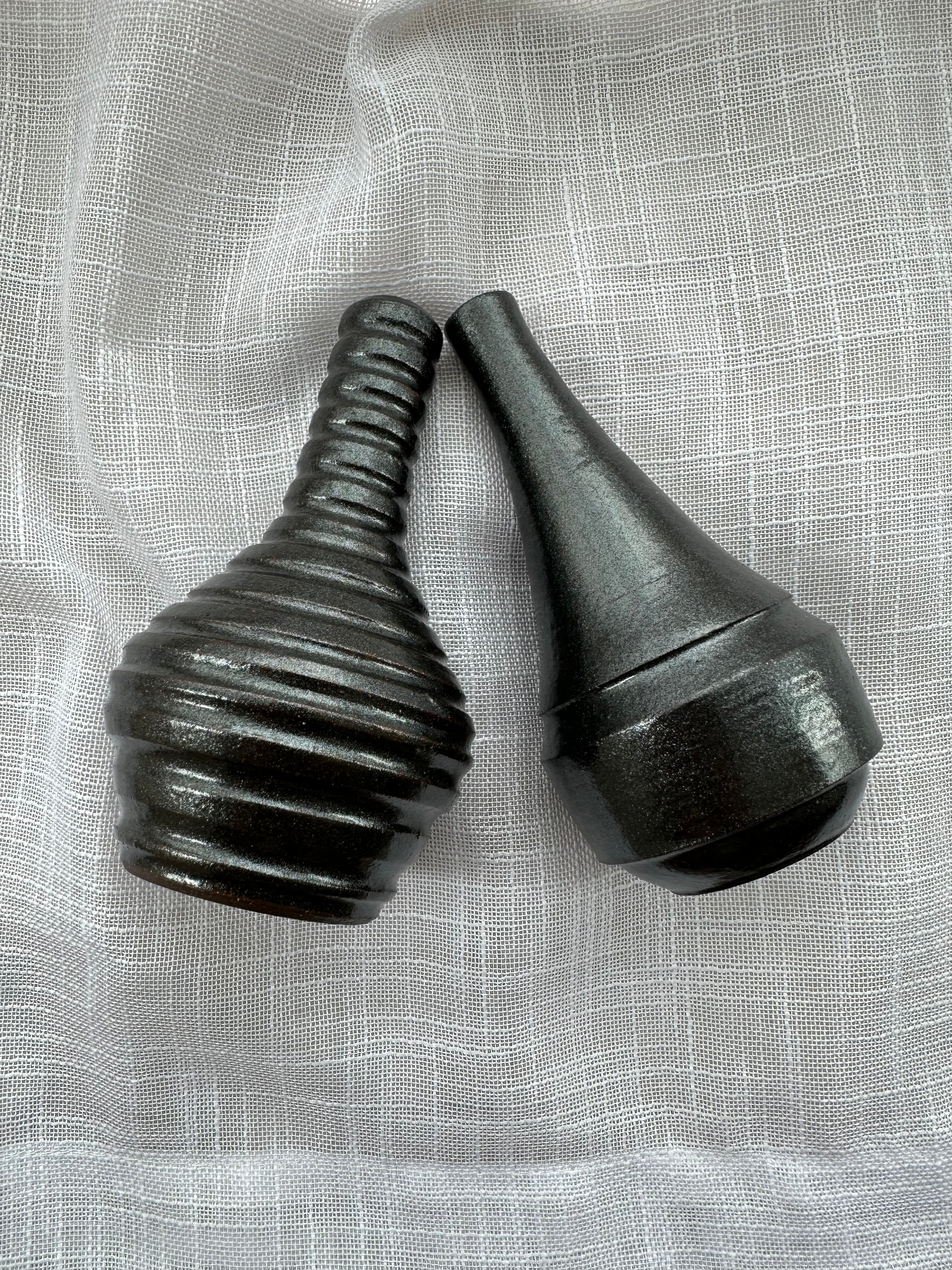 Two black ceramic vases on a textured gray background