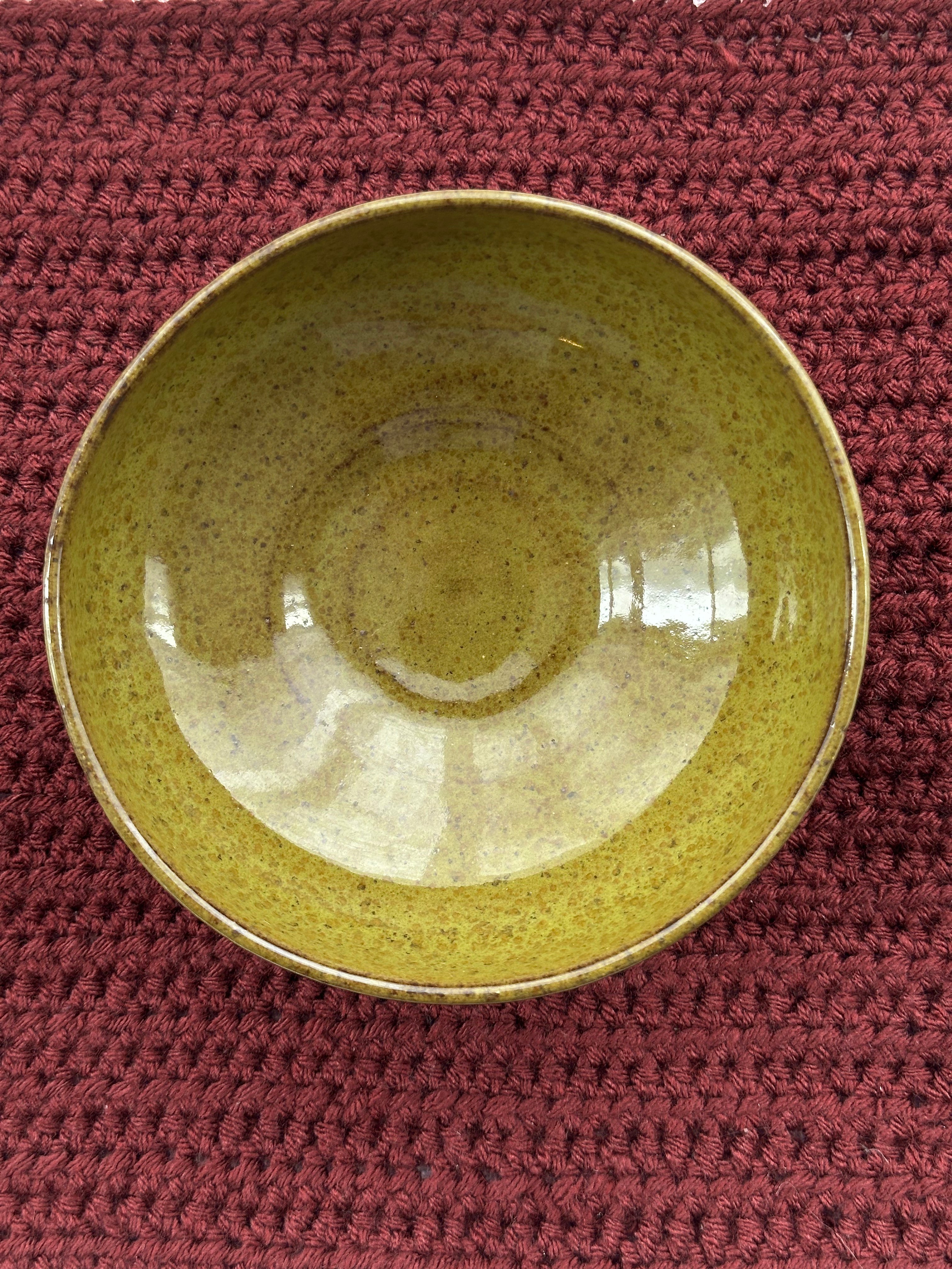 Green ceramic bowl on a textured red surface