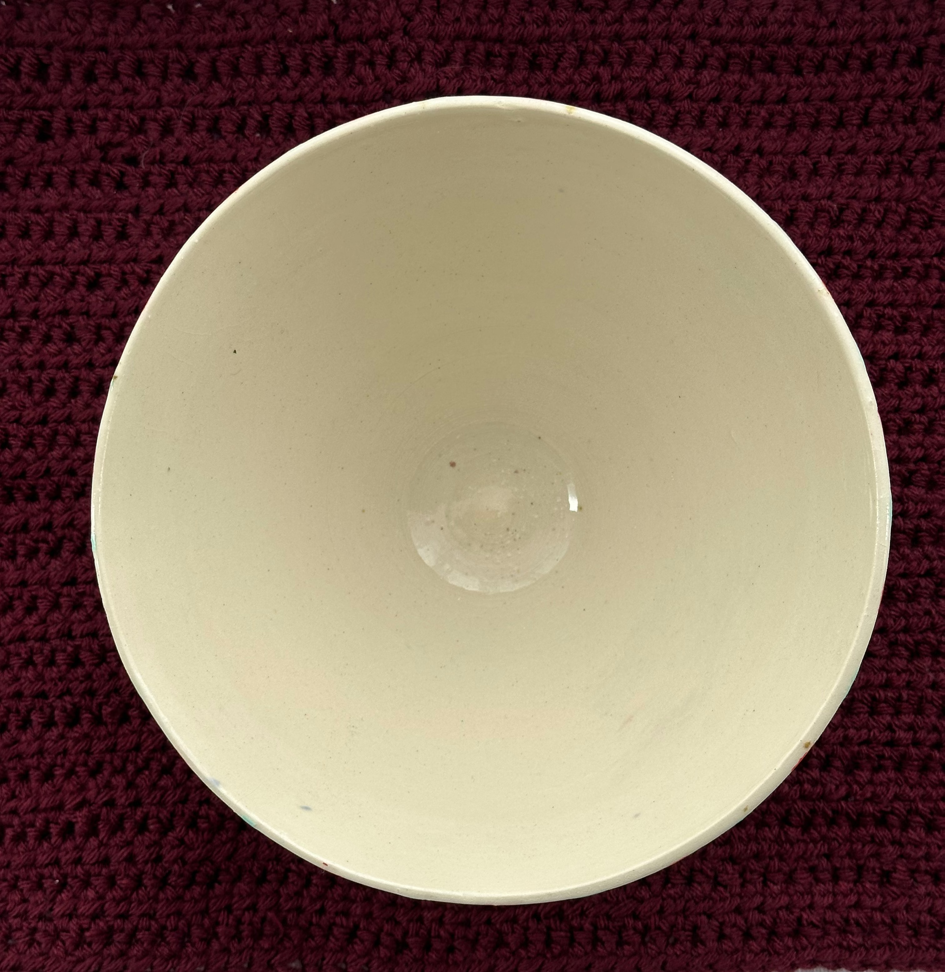 Beige ceramic bowl on a dark red woven mat