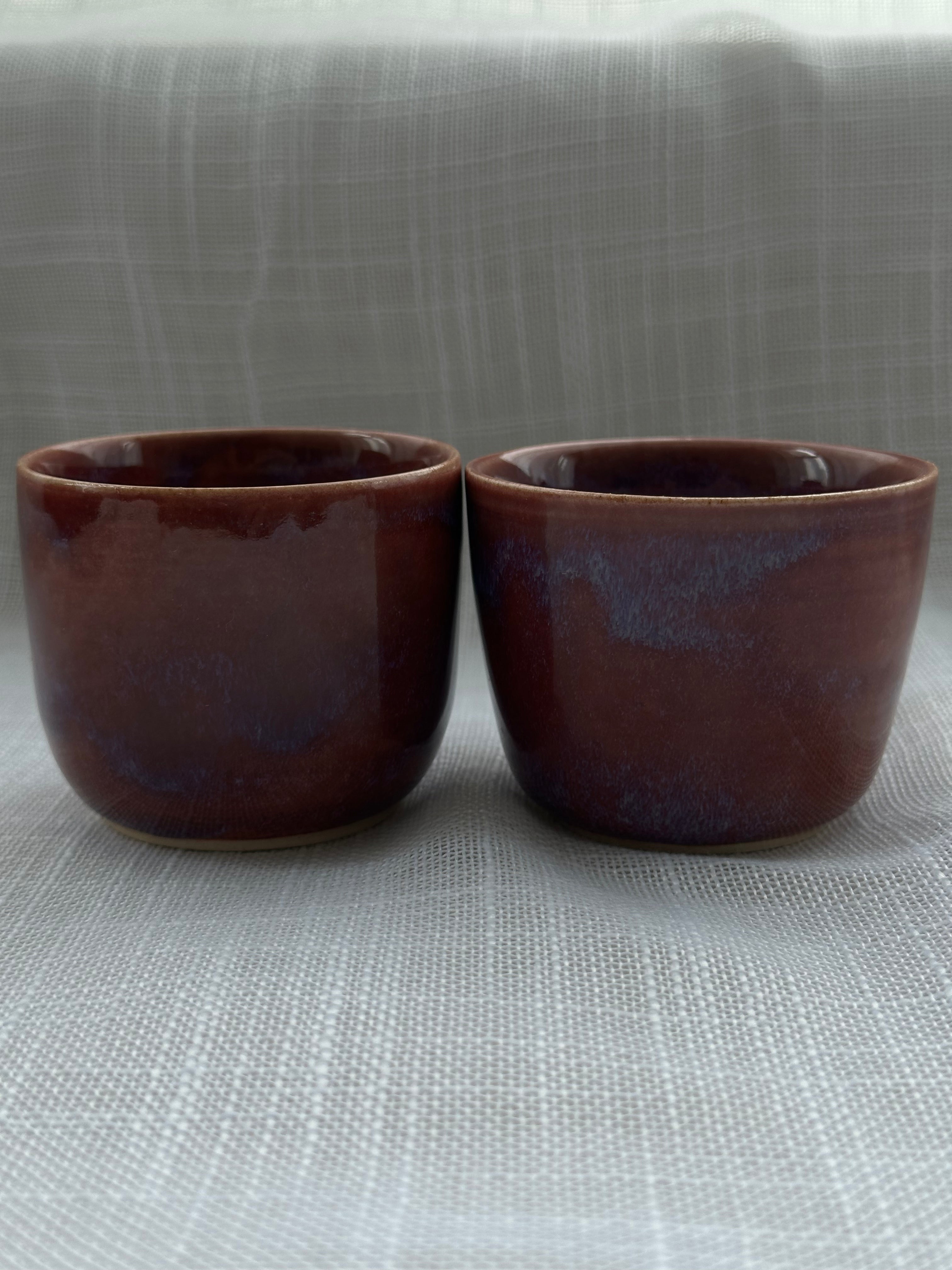 Two brown ceramic cups on a textured gray surface
