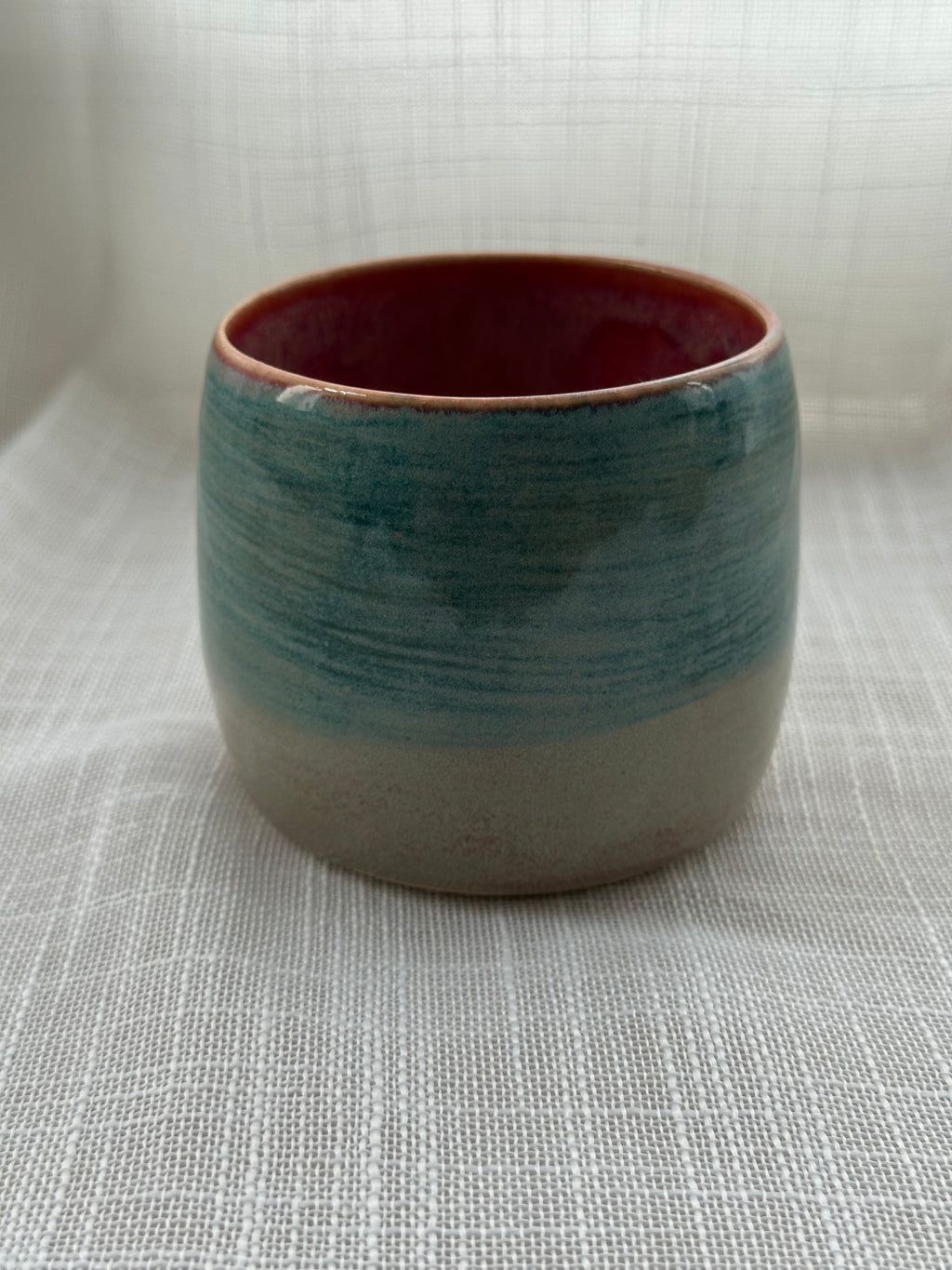 Ceramic cup with a gradient color from teal to gray on a textured surface