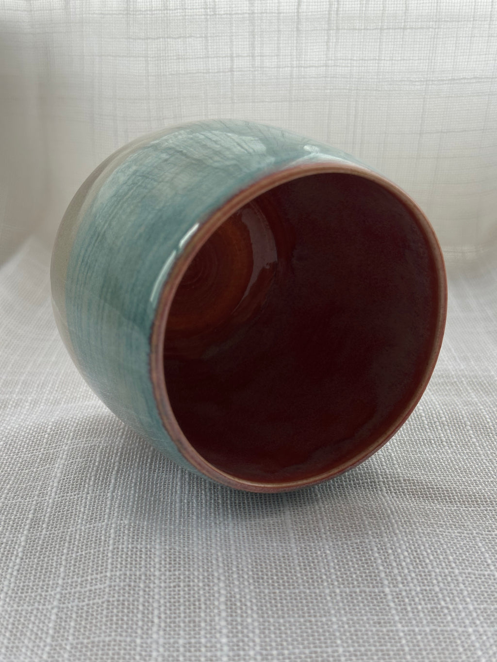 Ceramic mug with a gradient color from teal to gray on a textured white background