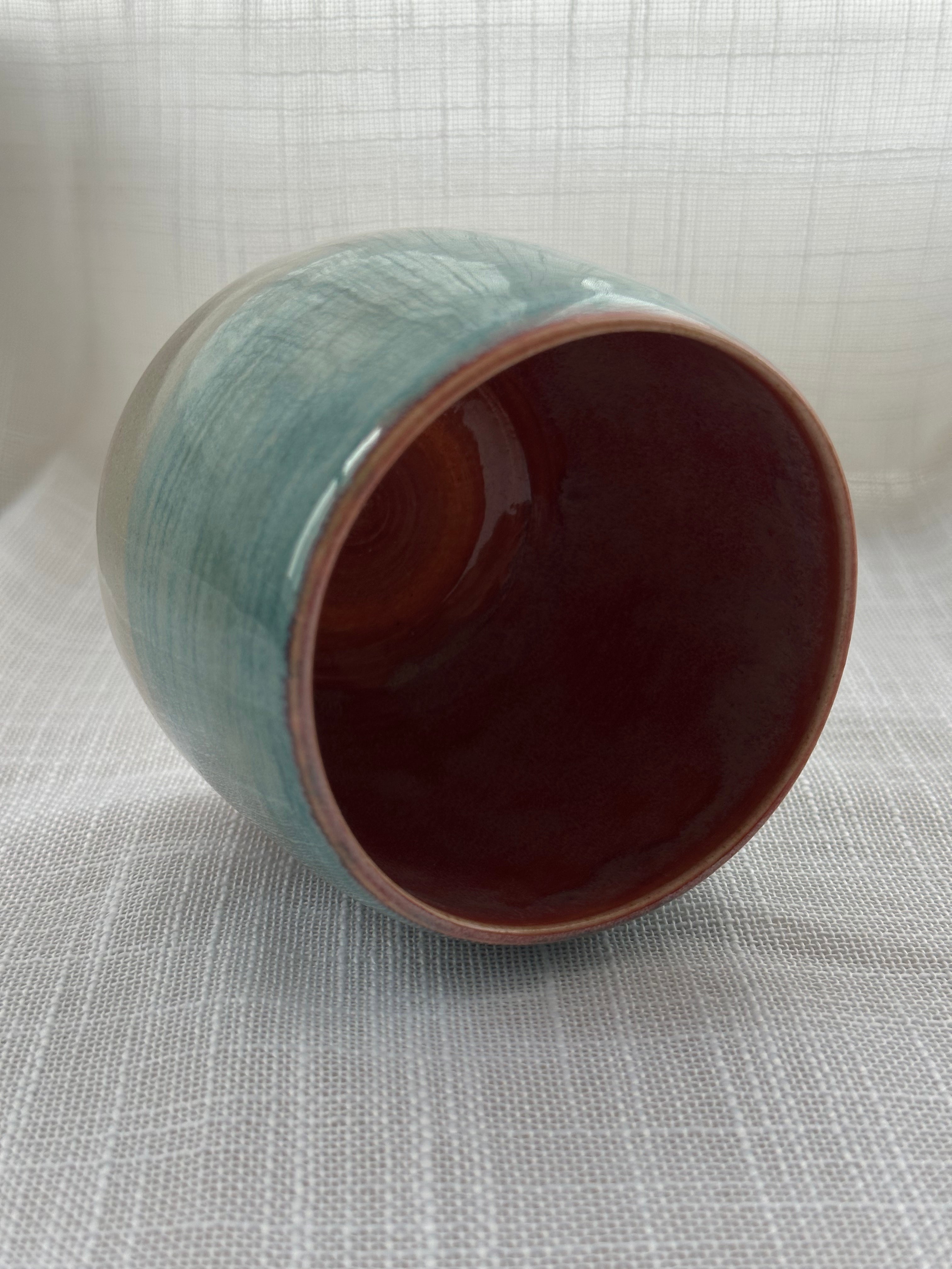 Ceramic mug with a gradient color from teal to gray on a textured white background