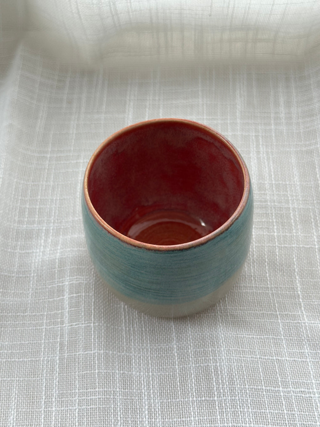 Ceramic cup with a rose interior on a textured white surface