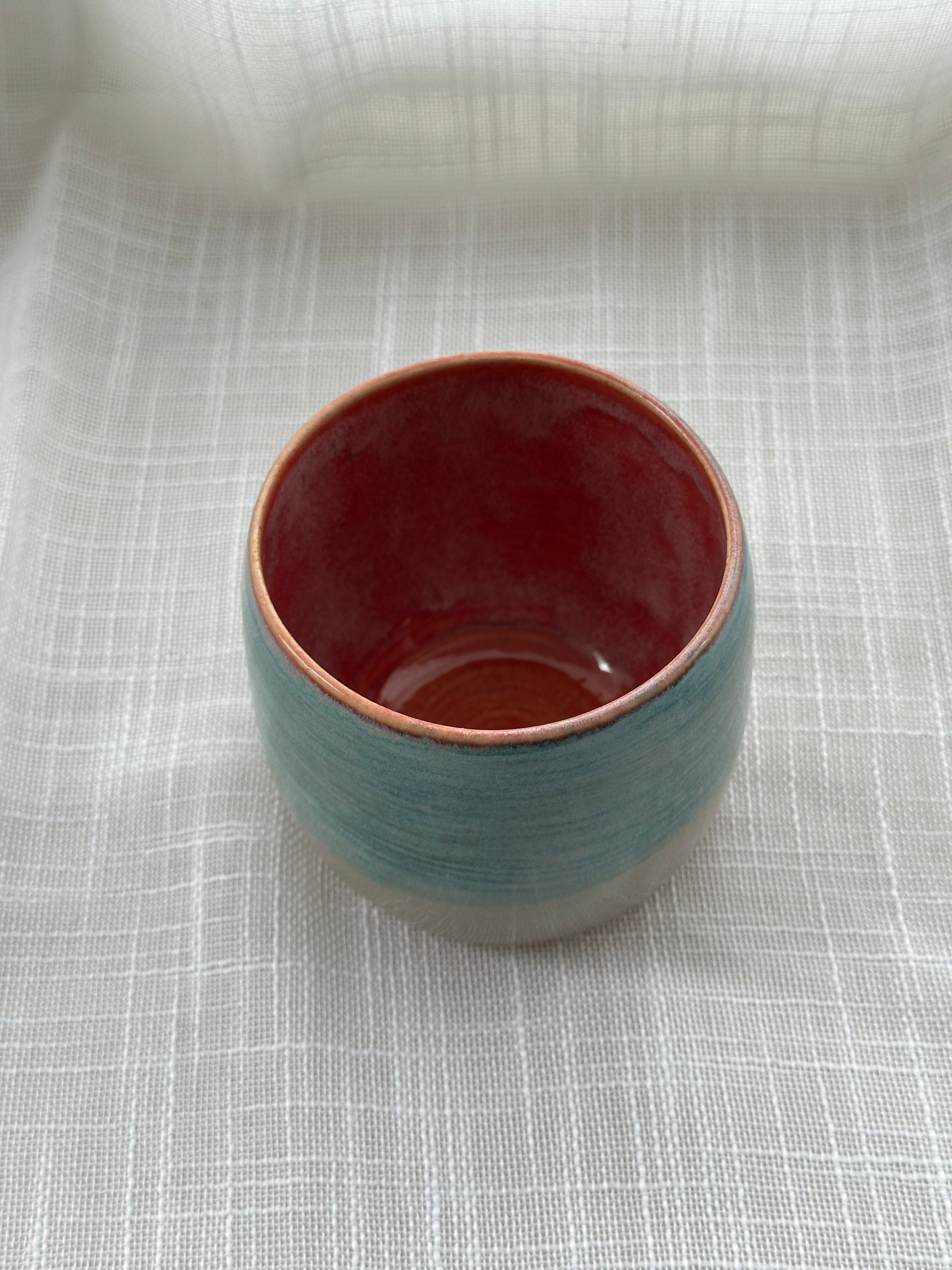 Ceramic cup with a rose interior on a textured white surface