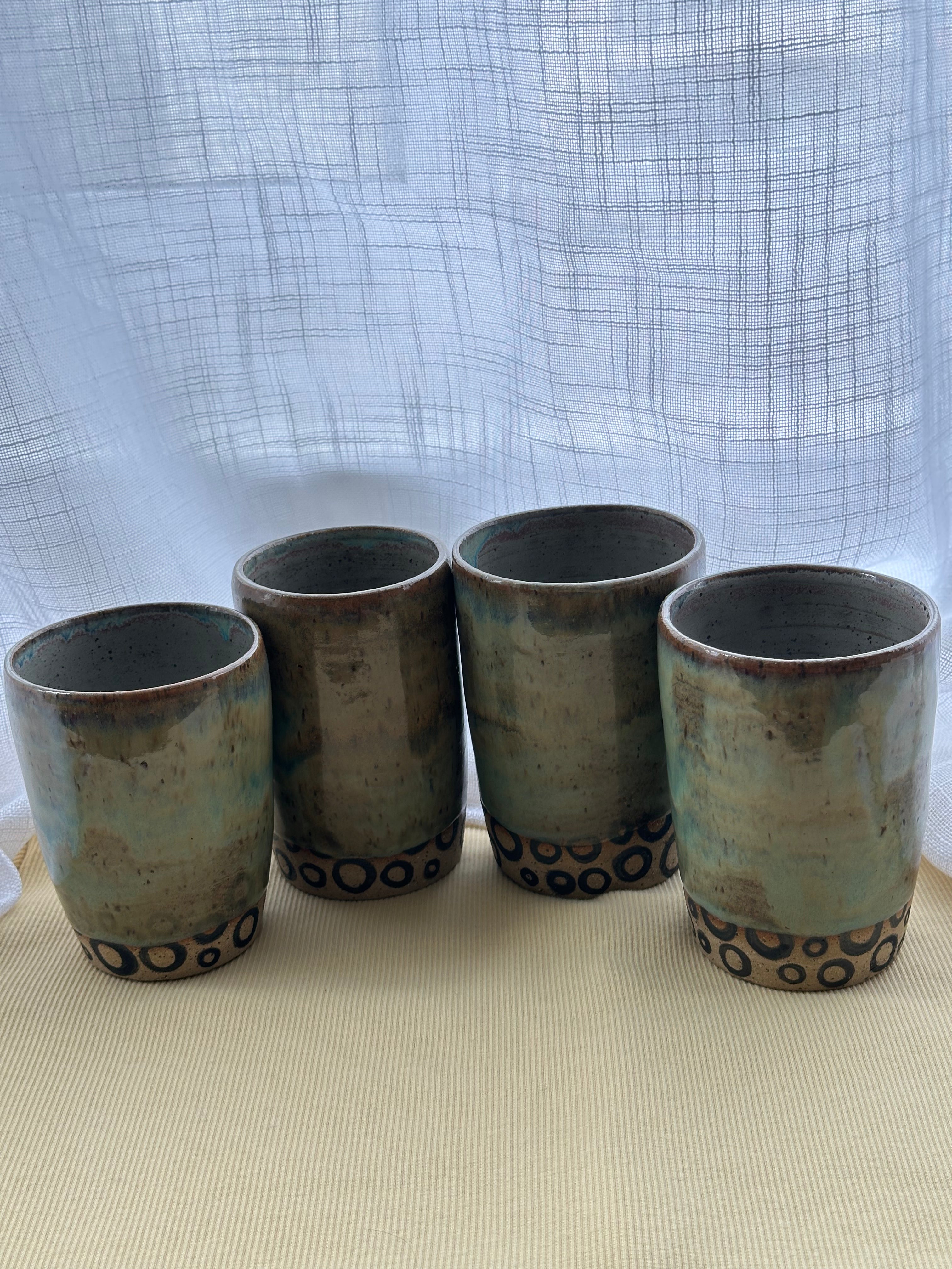 Set of four ceramic cups with decorative patterns on a light surface and blue textured background