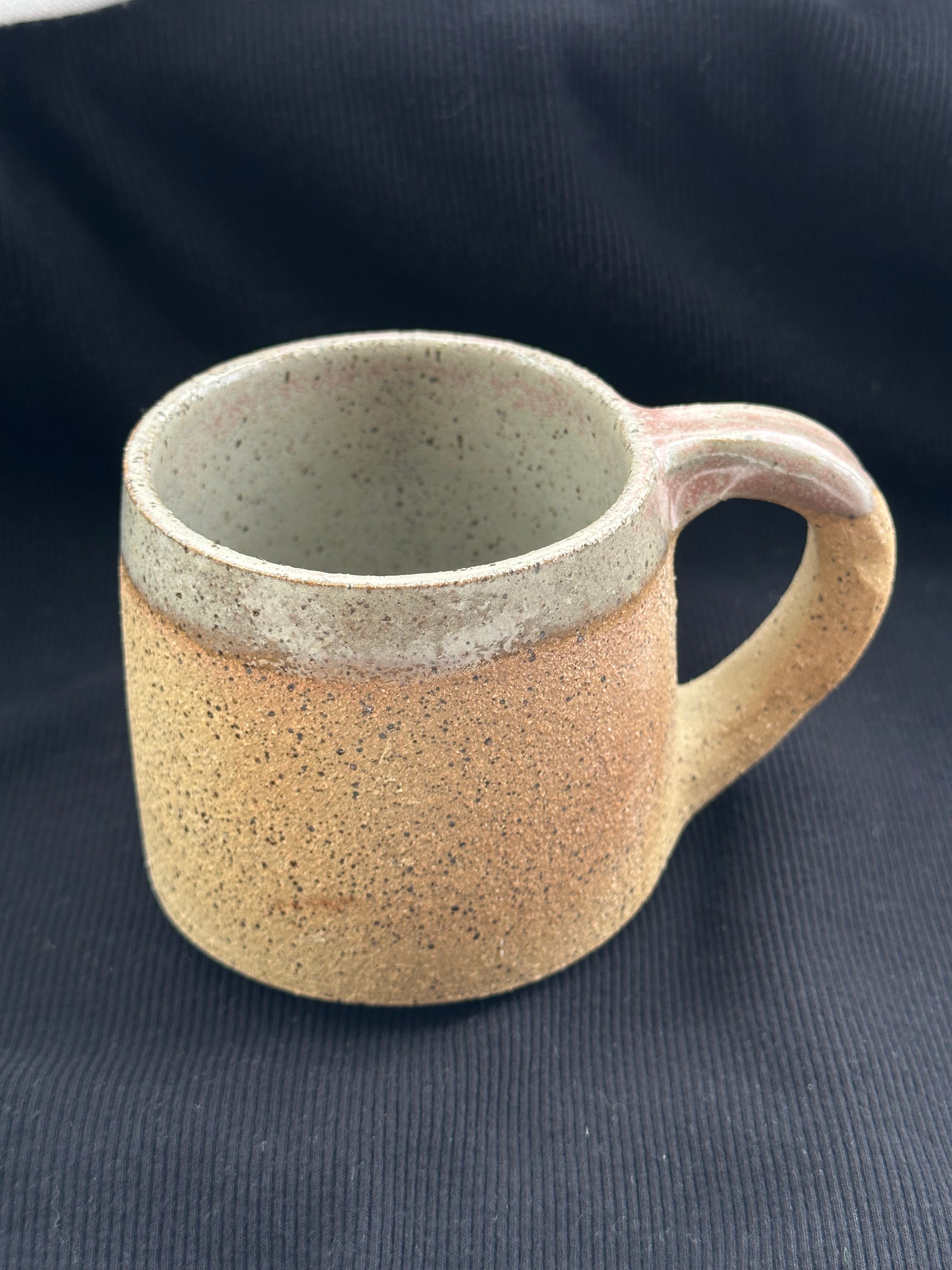Speckled ceramic mug on a dark fabric background