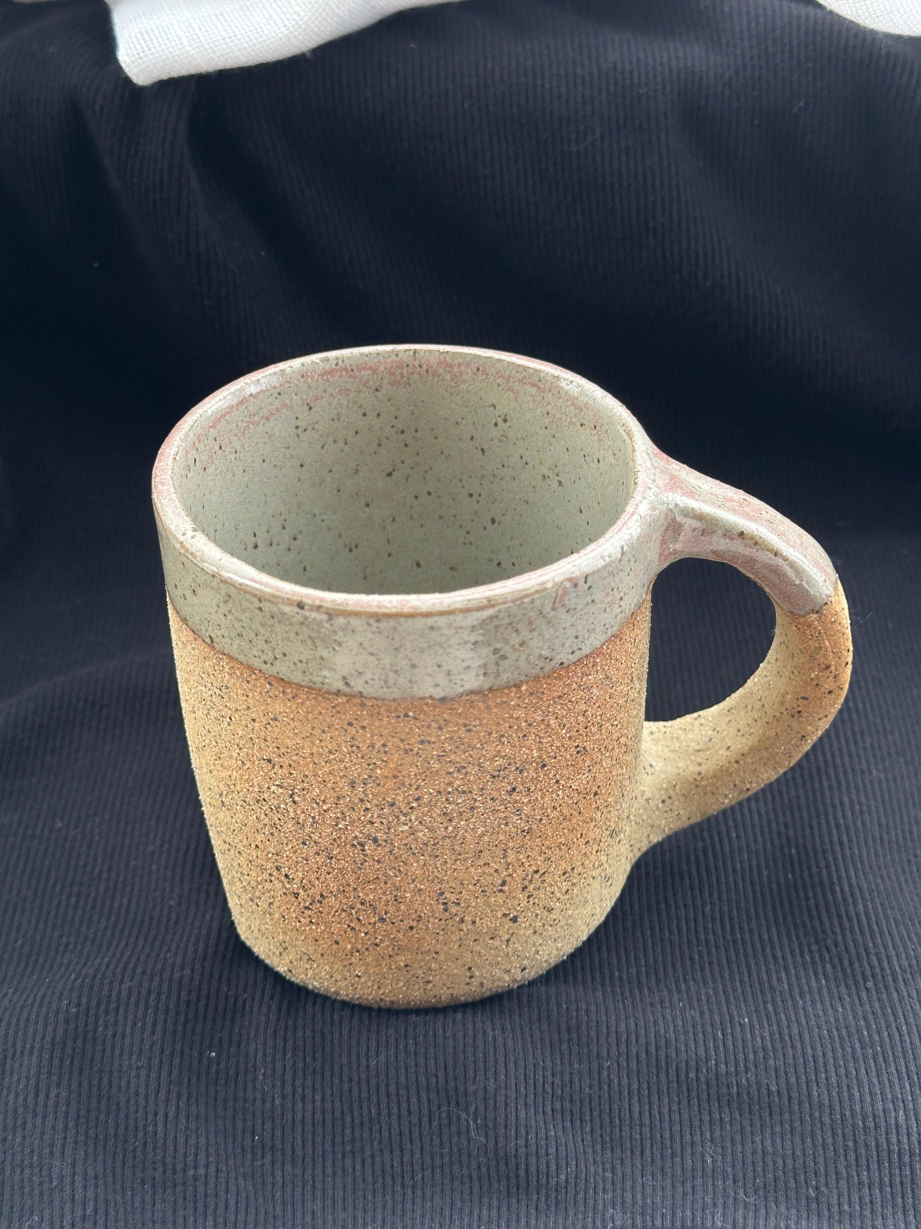 Speckled ceramic mug on a dark fabric background