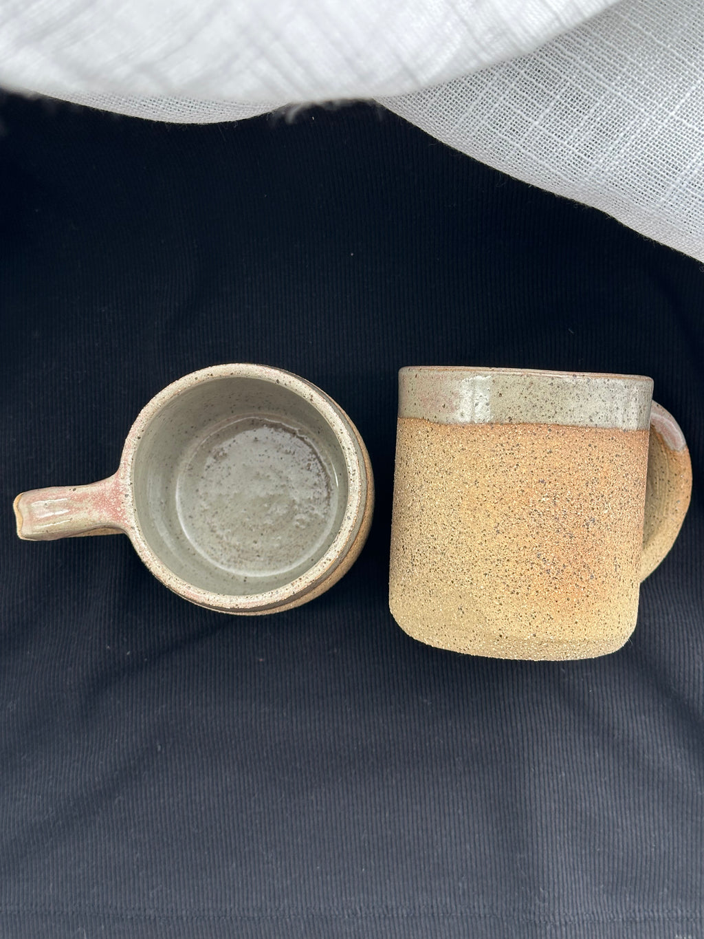Two ceramic mugs on a dark surface with a light gray background