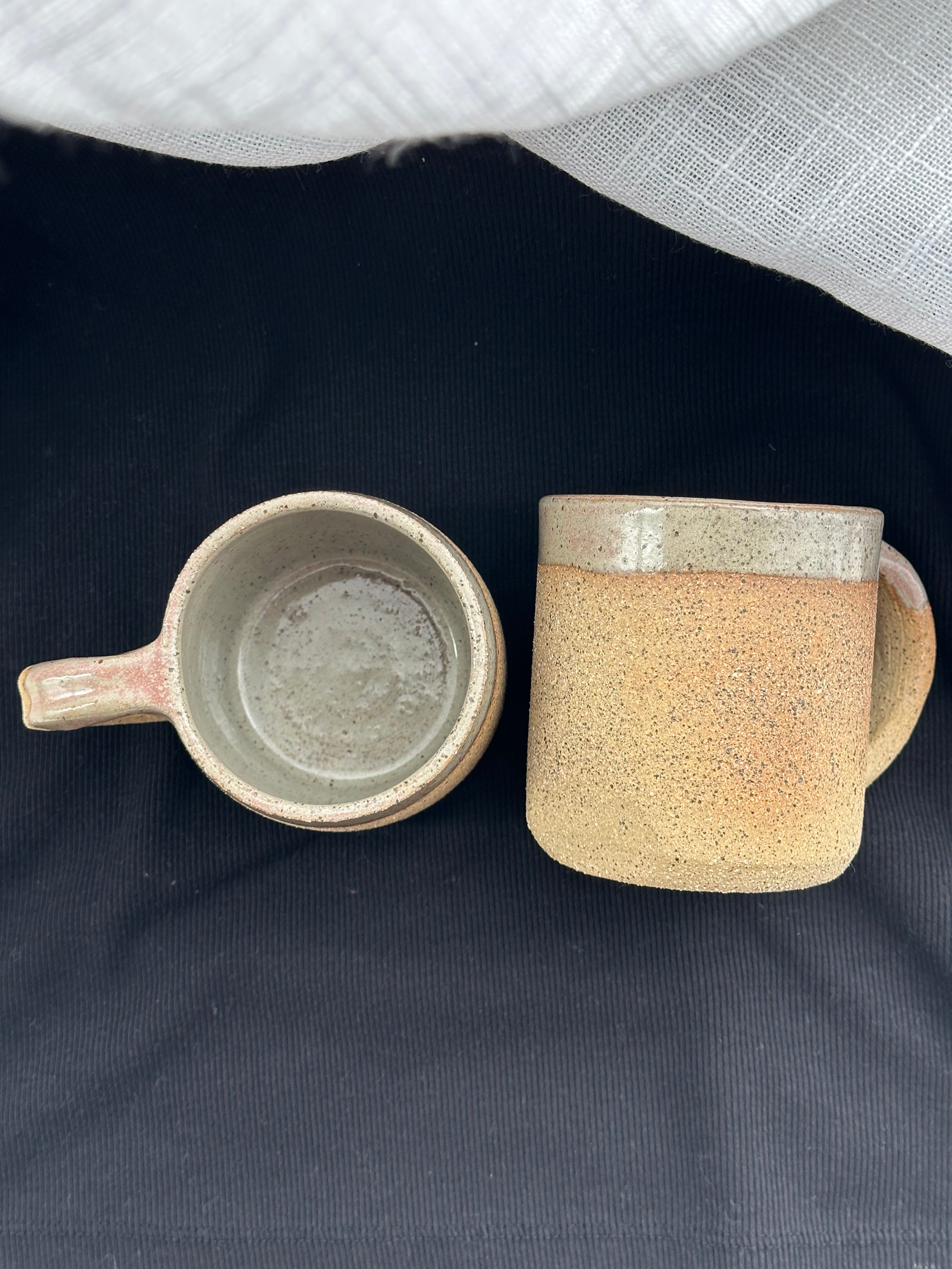 Two ceramic mugs on a dark surface with a light gray background